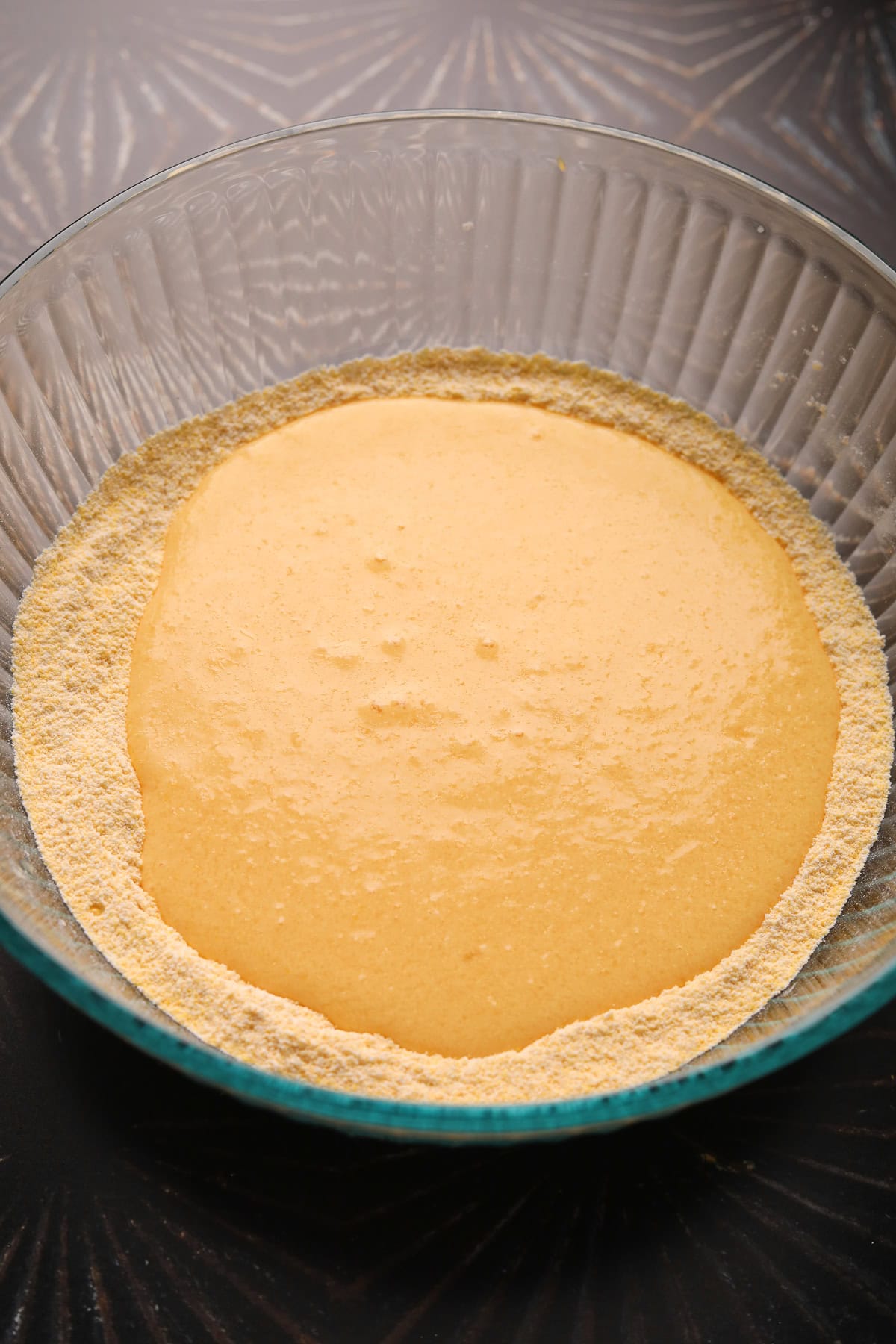 Dry and wet ingredients for cheddar jalapeño cornbread in a mixing bowl.