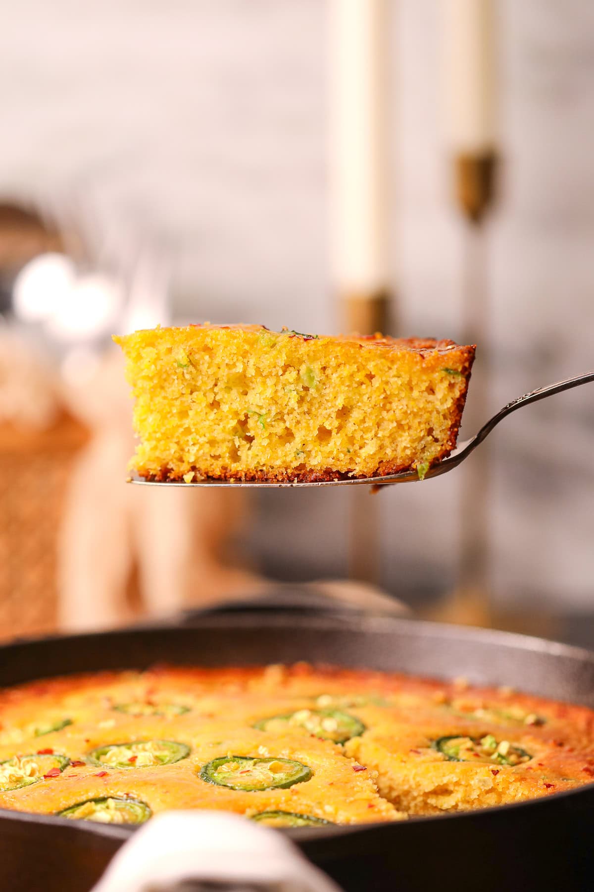 Side shot of a slice of jalapeño cheddar cornbread with spicy honey butter.
