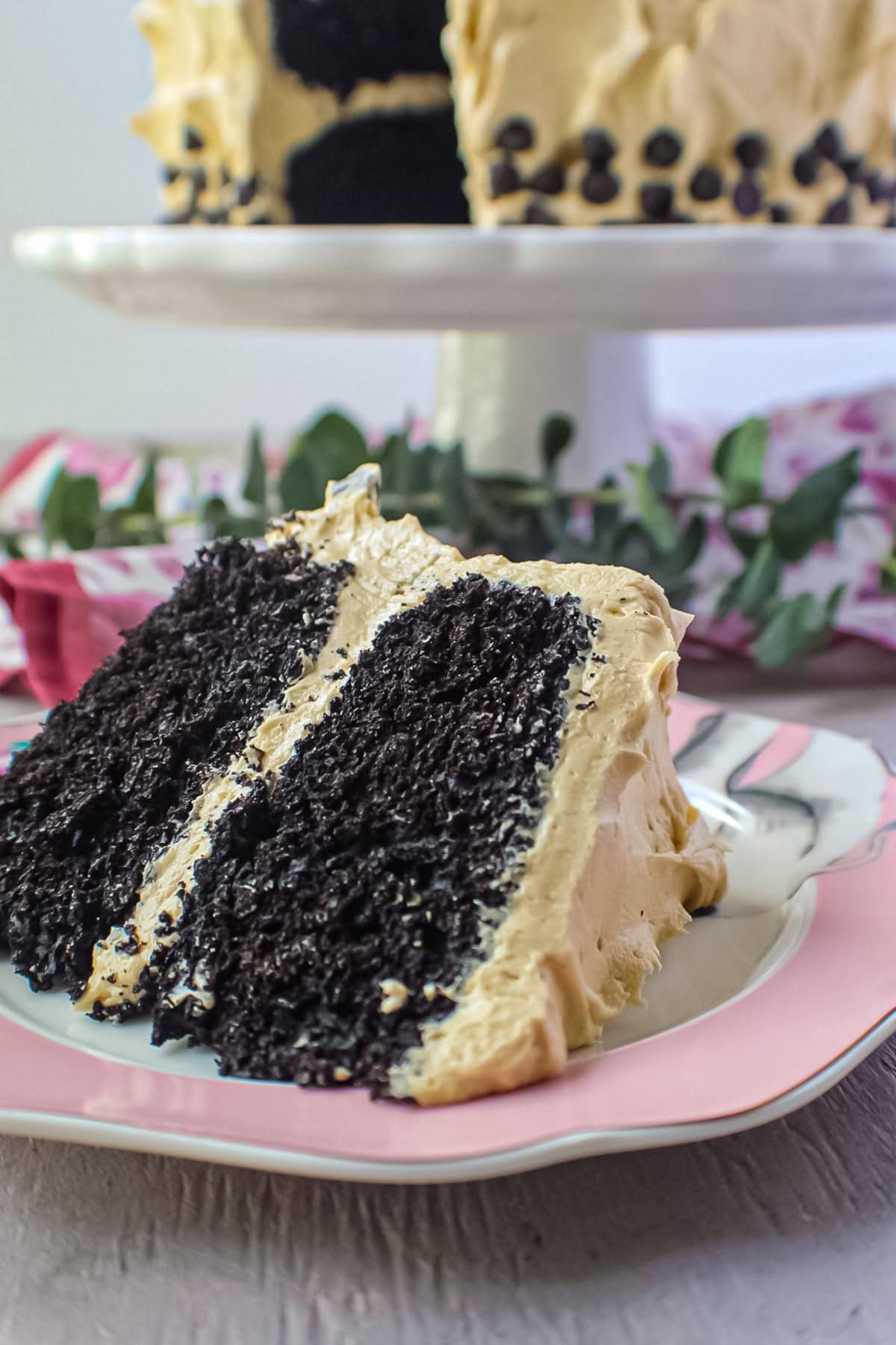 A slice of dark chocolate peanut butter layer cake on a dessert plate.