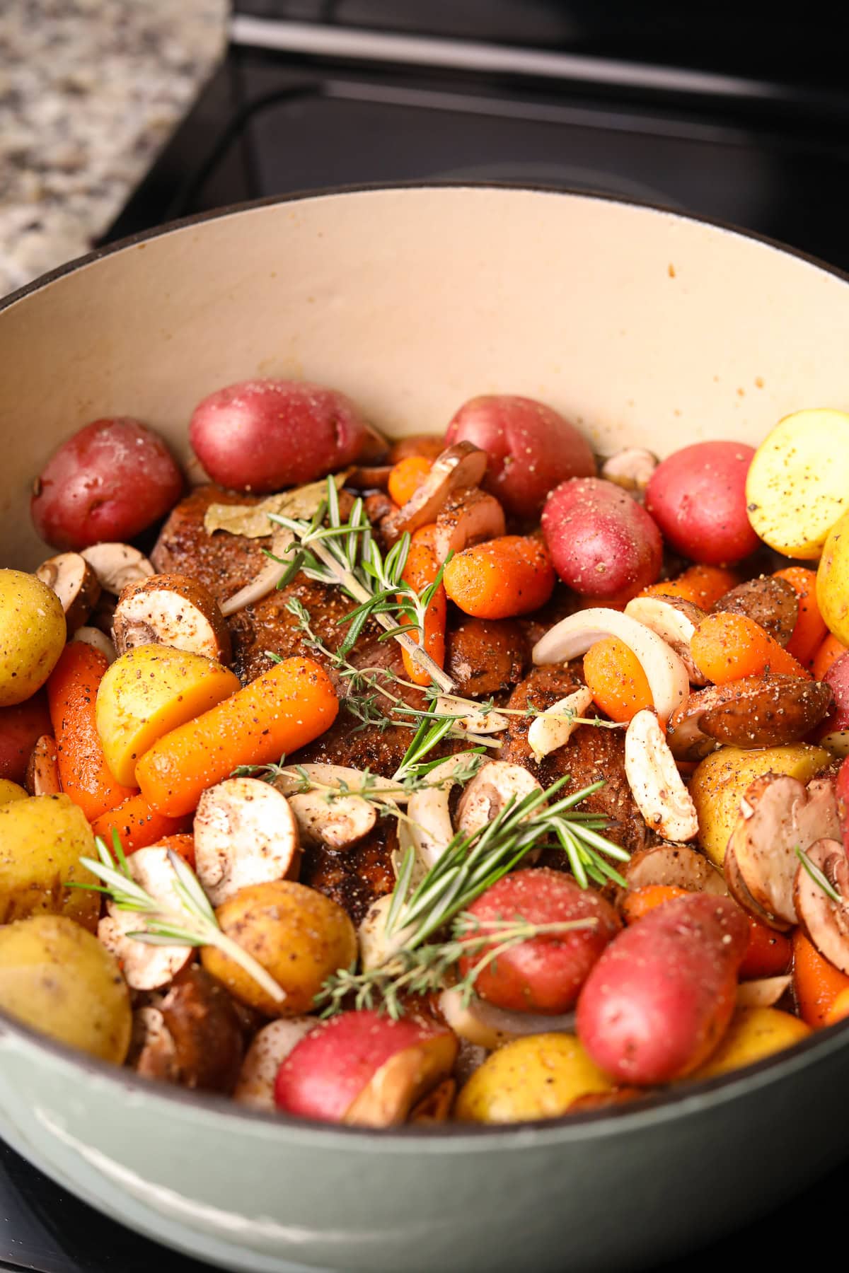  Dutch oven with vegetables and herbs before going in the oven.