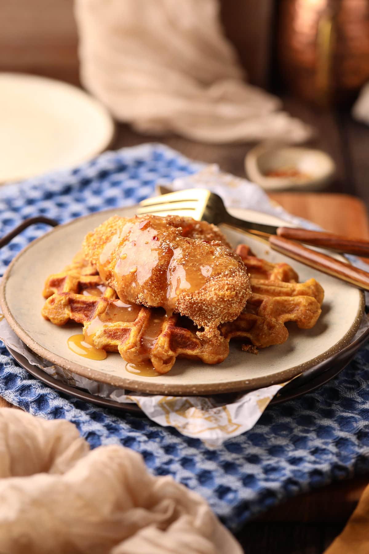 Sweet potato waffles, with fried catfish and spicy honey butter on a gray plate on a table top.