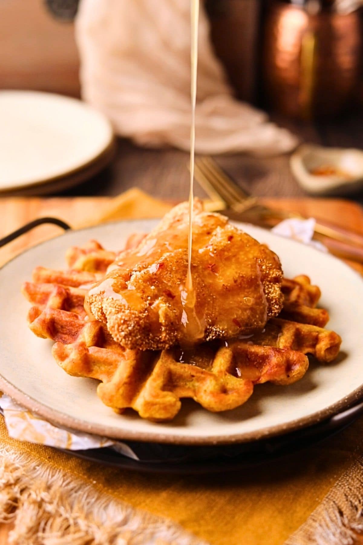 Spicy honey butter, being drizzled over fried catfish and sweet potato waffles.