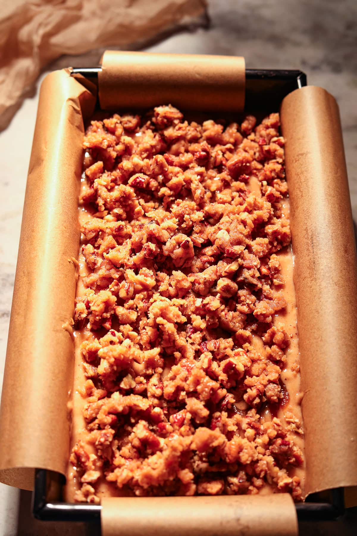 Apple butter, banana bread with pecan streusel topping in a loaf pan before going into the oven.