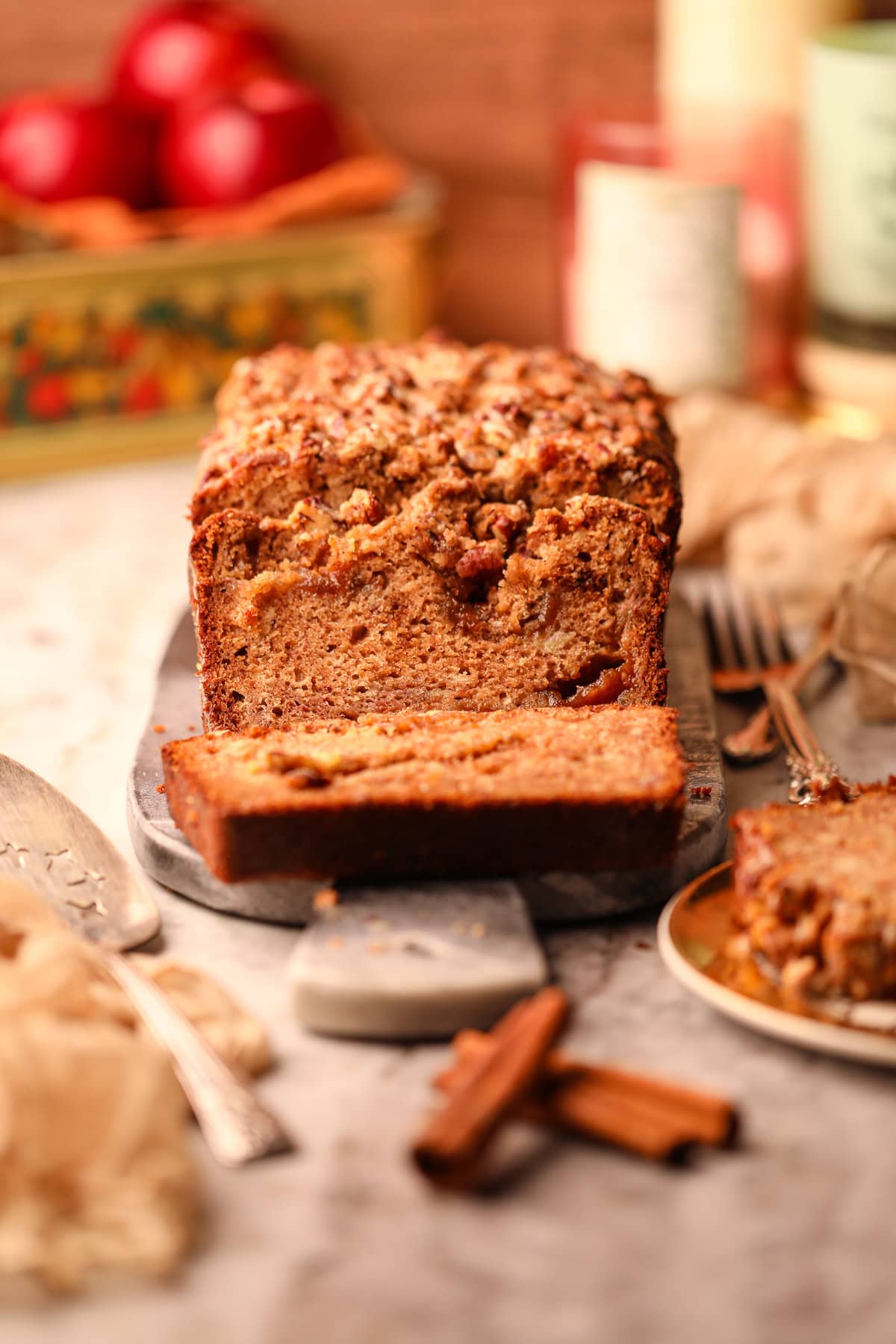 Apple butter, banana bread with pecan streusel on a serving board sitting on a table top.