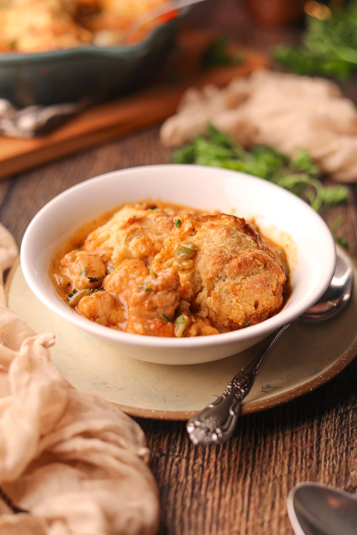 A serving of catfish etouffee pot pie in a white bowl sitting on a table top.