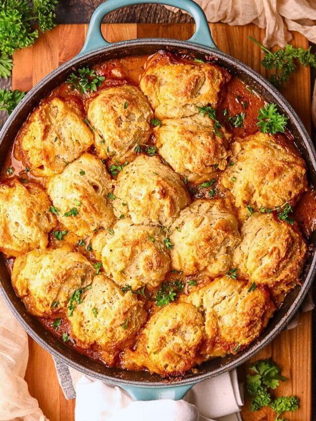 Catfish etouffee pot pie in a cast iron skillet, sitting on a wooden cutting board.