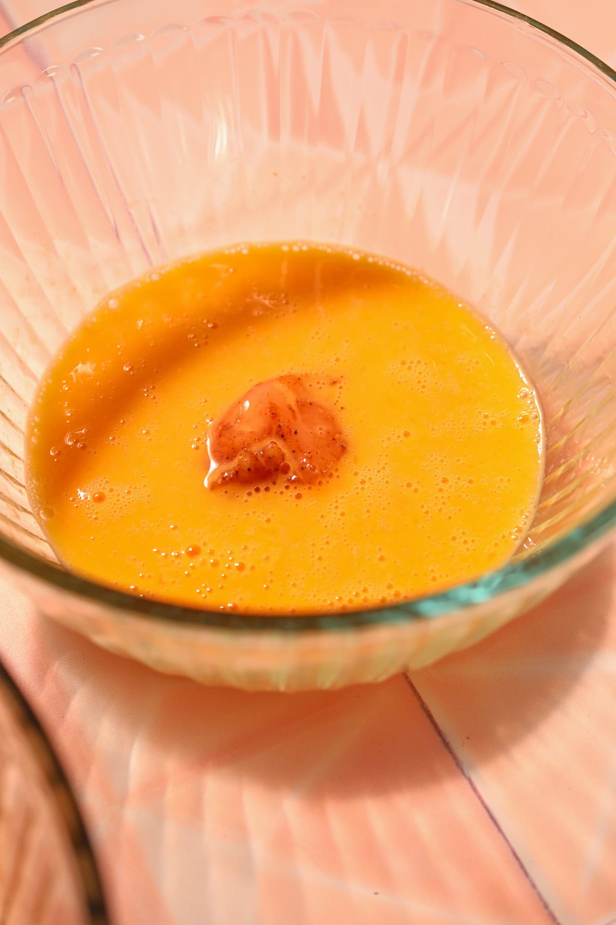 Raw chicken chunk in egg wash in a bowl.