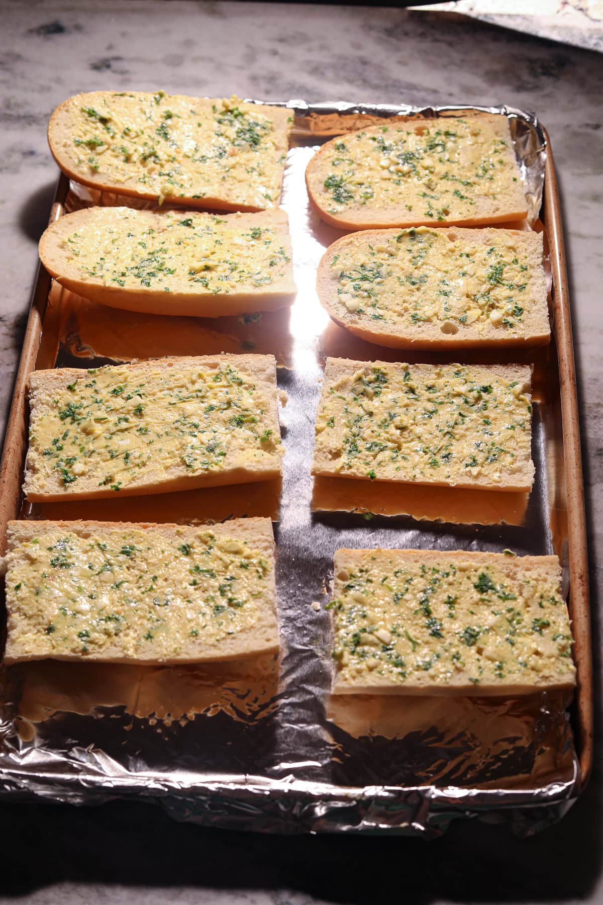 Baguettes covered in garlic butter before being toasted.