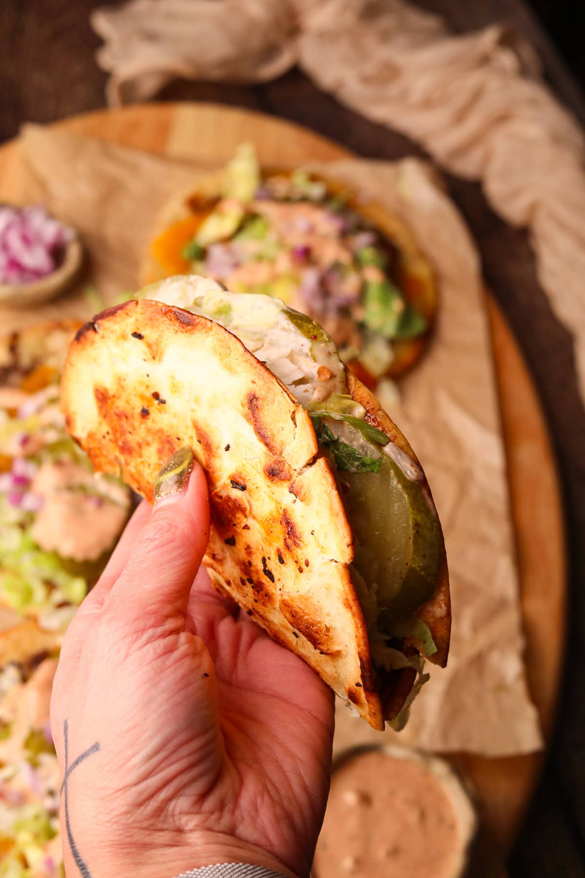 Folded smash burger taco held in hand.