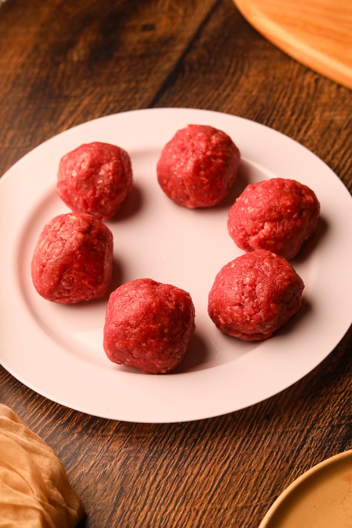 Ground beef balls on a plate for Smashburger tacos.