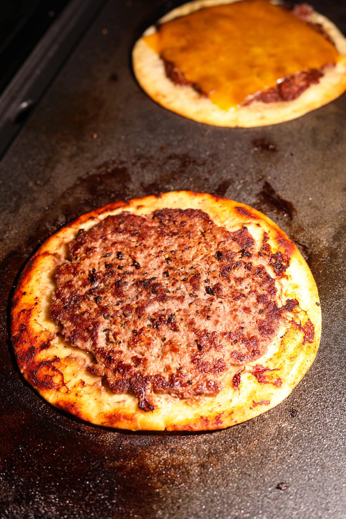 Smashburger tacos cooking on a griddle.