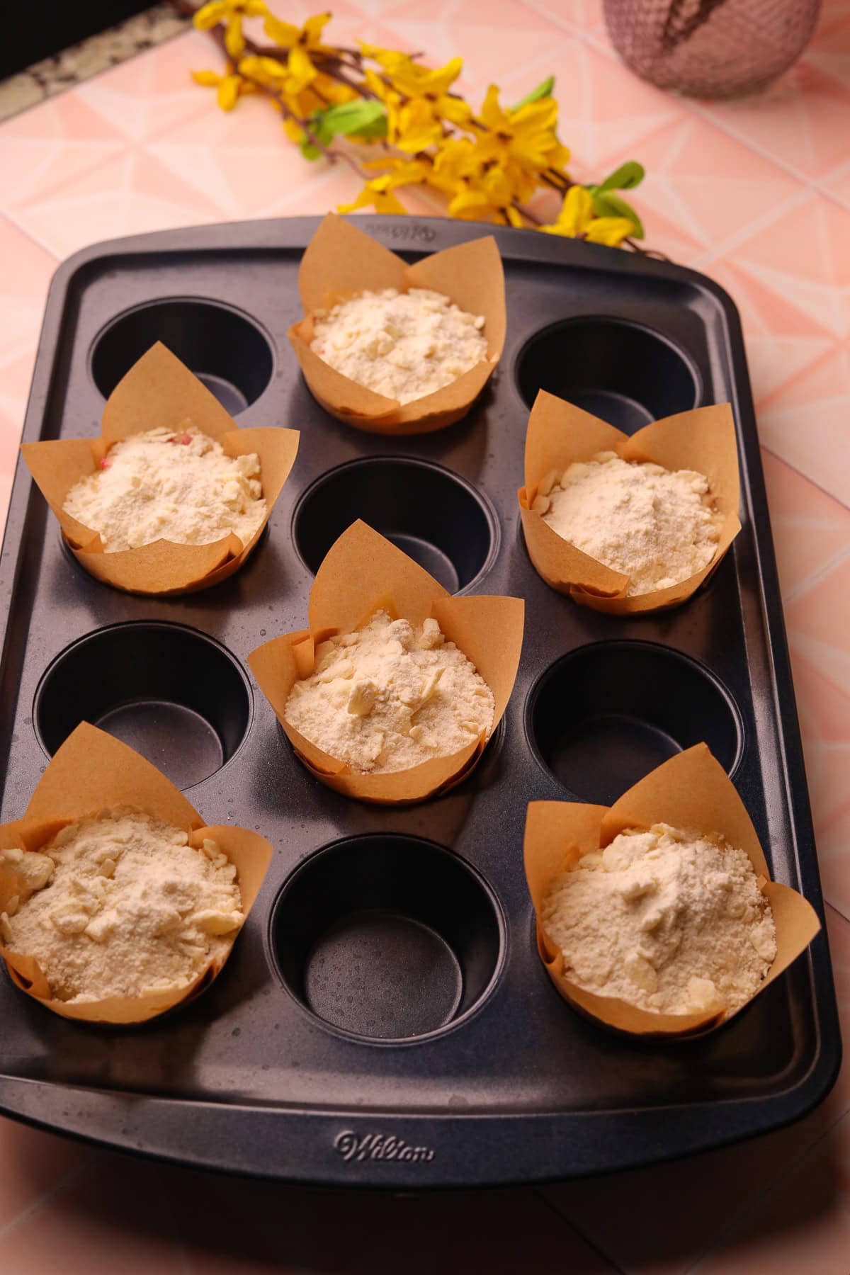 Strawberry shortcake muffins with crumble topping before going in the oven.