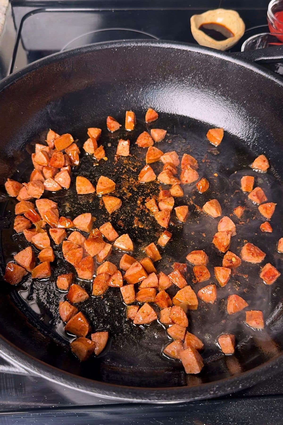 Smoked sausage, browning in a pan.