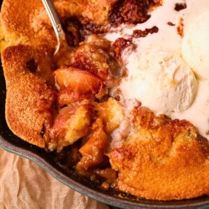 Southern skillet, peach cobbler with a serving spoon to show detail.
