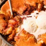Southern skillet, peach cobbler with a serving spoon to show detail.