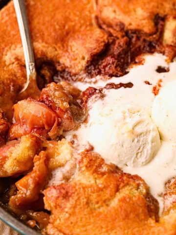 Southern skillet, peach cobbler with a serving spoon to show detail.