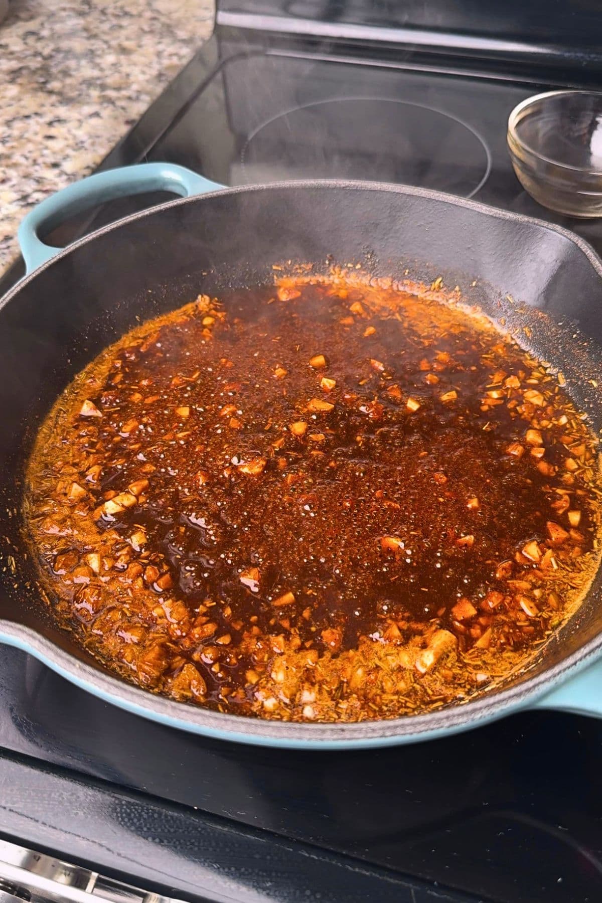 New Orleans bbq shrimp sauce, simmering in a pan.