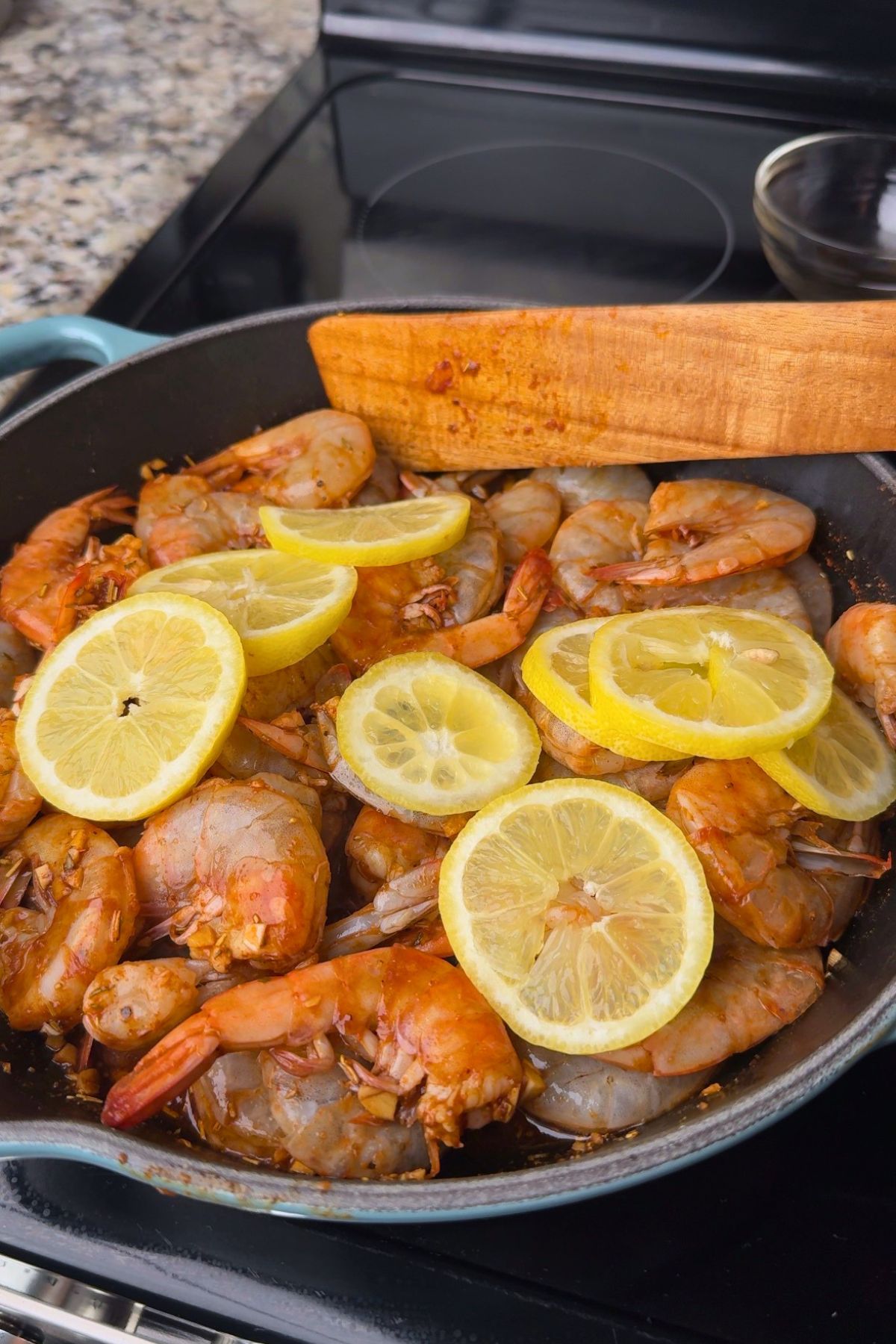 Shrimp simmering with lemon slices for New Orleans BBQ shrimp.