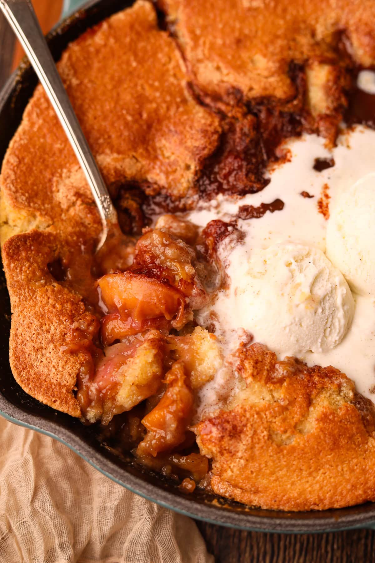 Southern skillet, peach cobbler with a serving spoon to show detail.