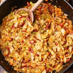 Southern fried cabbage with bacon in a skillet with serving spoon.