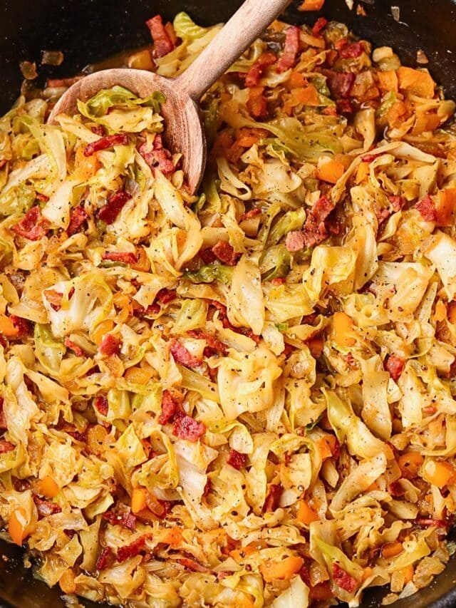 Southern fried cabbage with bacon in a skillet with serving spoon.
