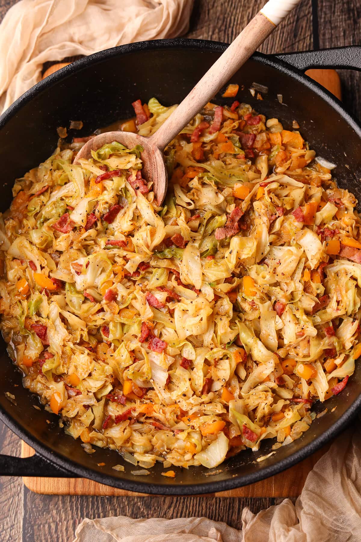 Southern fried cabbage with bacon in a skillet with serving spoon. 