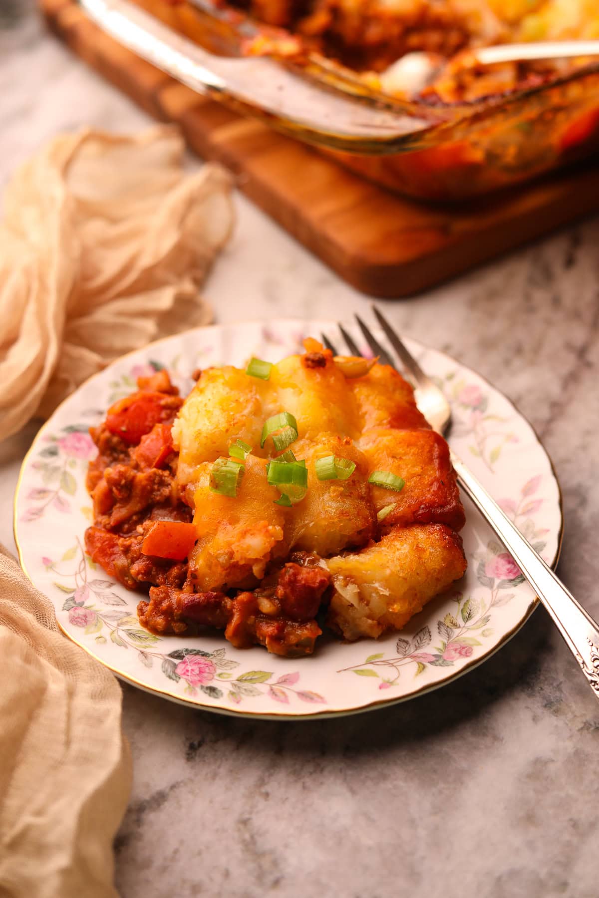 Chili cheese, tater tot casserole, serving on a plate with a fork. 
