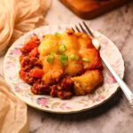Chili cheese, tater tot casserole, serving on a plate with a fork.