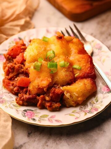 Chili cheese, tater tot casserole, serving on a plate with a fork.