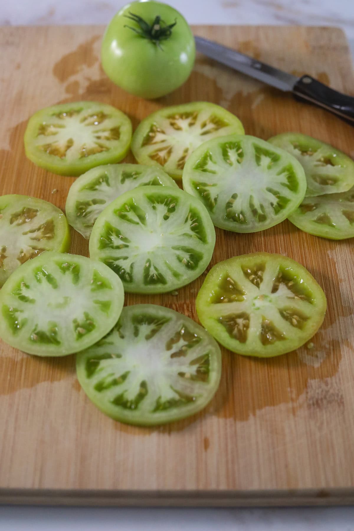 Sliced green tomatoes on a cutting board.